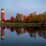 Trees with fall color are also reflected in a pond. The carillon is in the background.